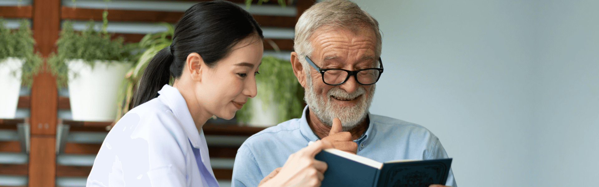 elderly man and caregiver reading a book